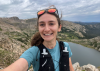 A selfie of Taylor Young while trail running on the High Lonesome Loop with a cool lake in the background.